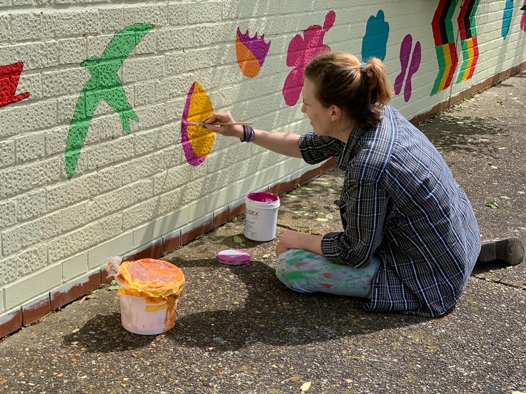 Playground wall mural – a local resident volunteer painting the design:
