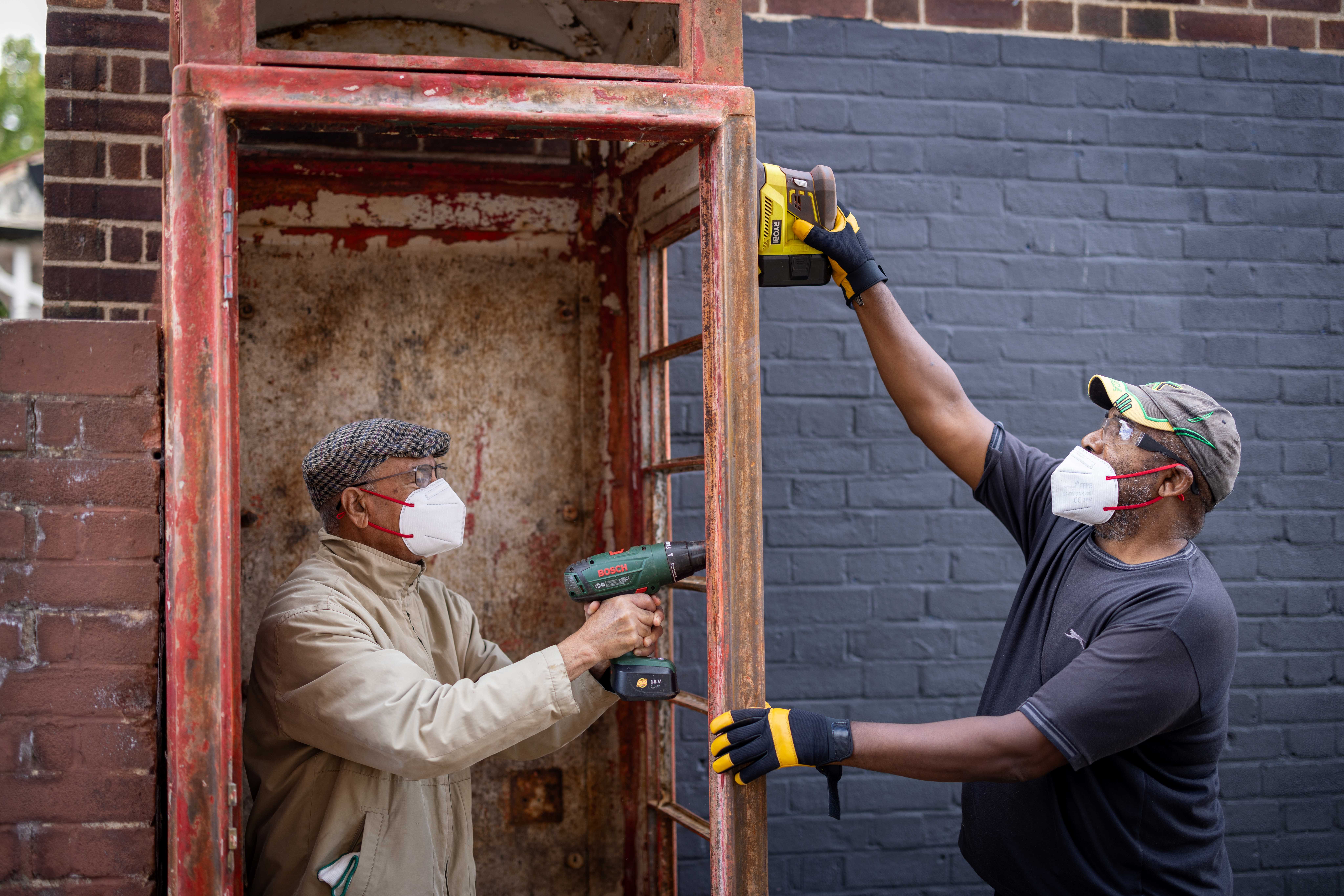 Two men carrying out maintenance on a phone box