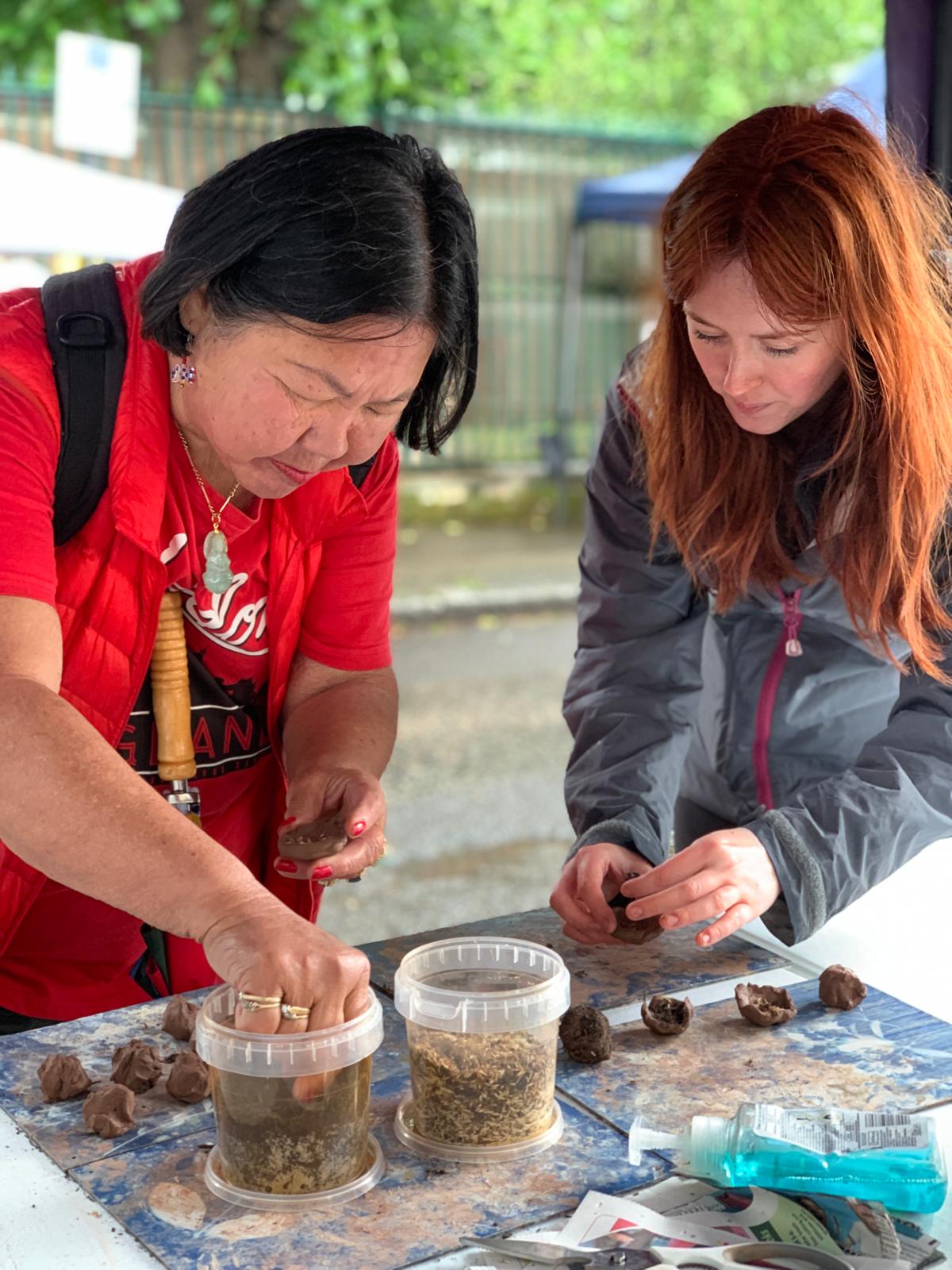 member of the public learning how to make a wildflower seed bomb from a volunteer