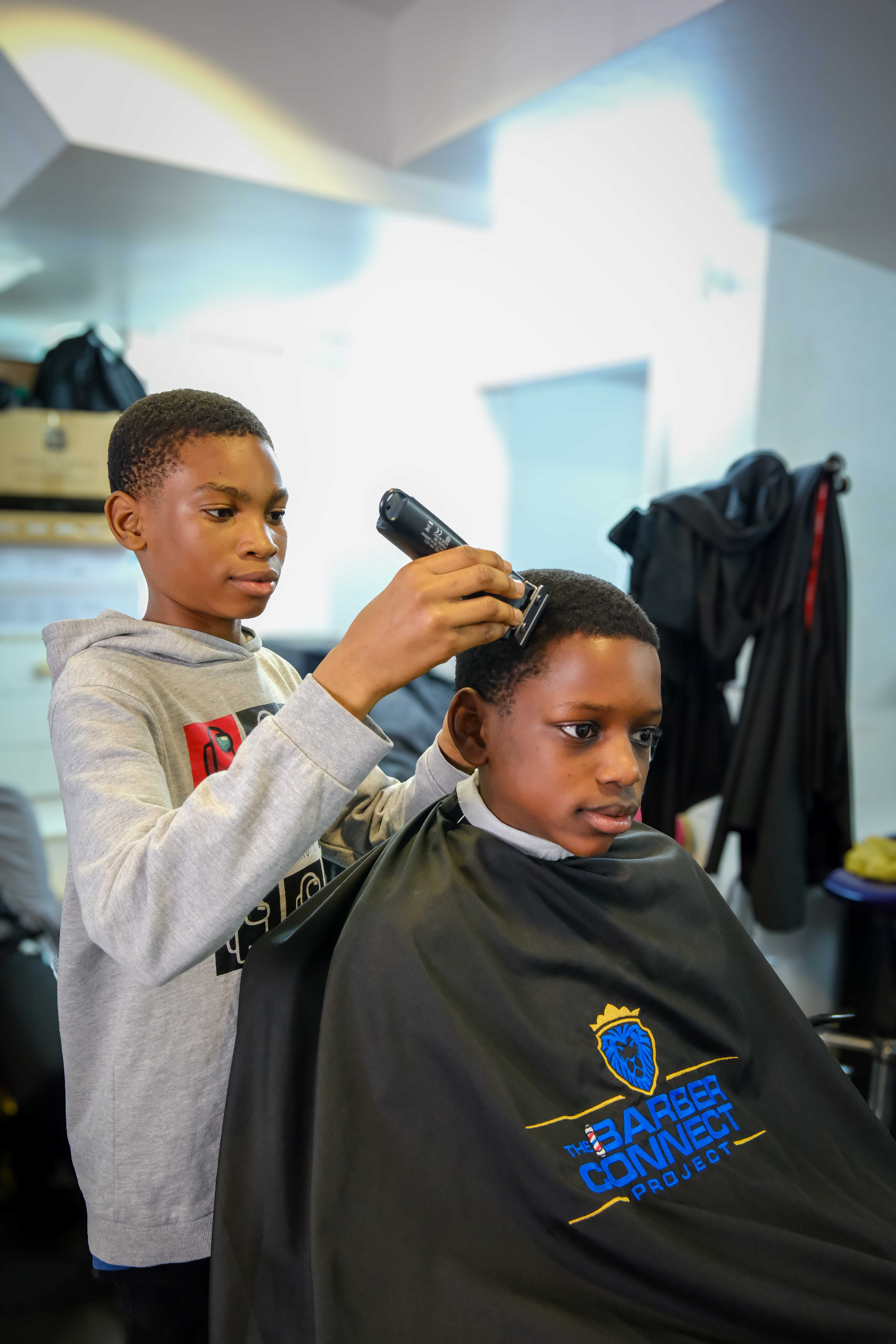 Young person shaving someone's hair